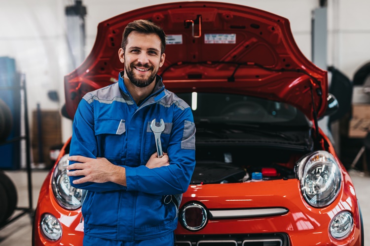 mechanic holding wrench in front of open car hood