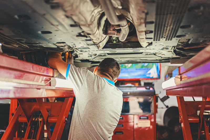 mechanic inspecting bottom of car